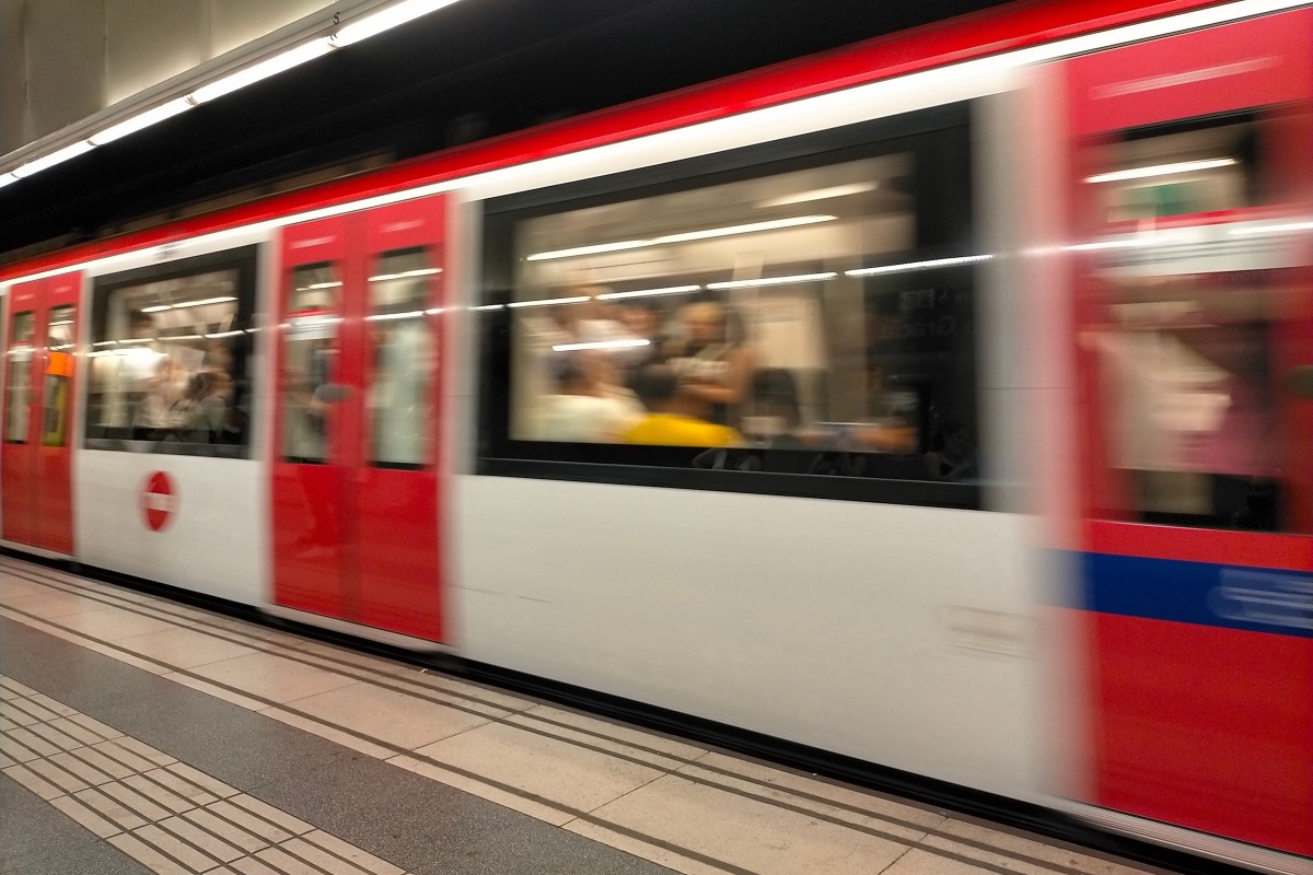 Rot-weißer Metro-Zug fährt in eine U-Bahn-Station in Barcelona ein